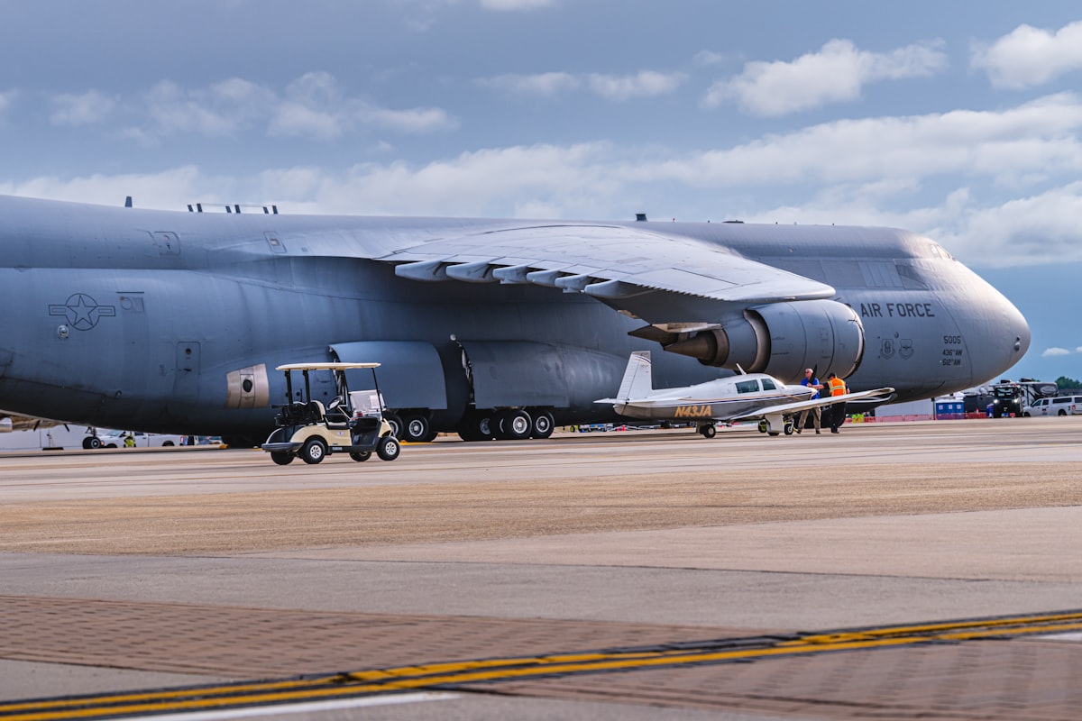 USAF C-5M Super Galaxy strategic airlifter on the ramp alongside a civilian aircraft, showing the massive scale of Air Force cargo aircraft